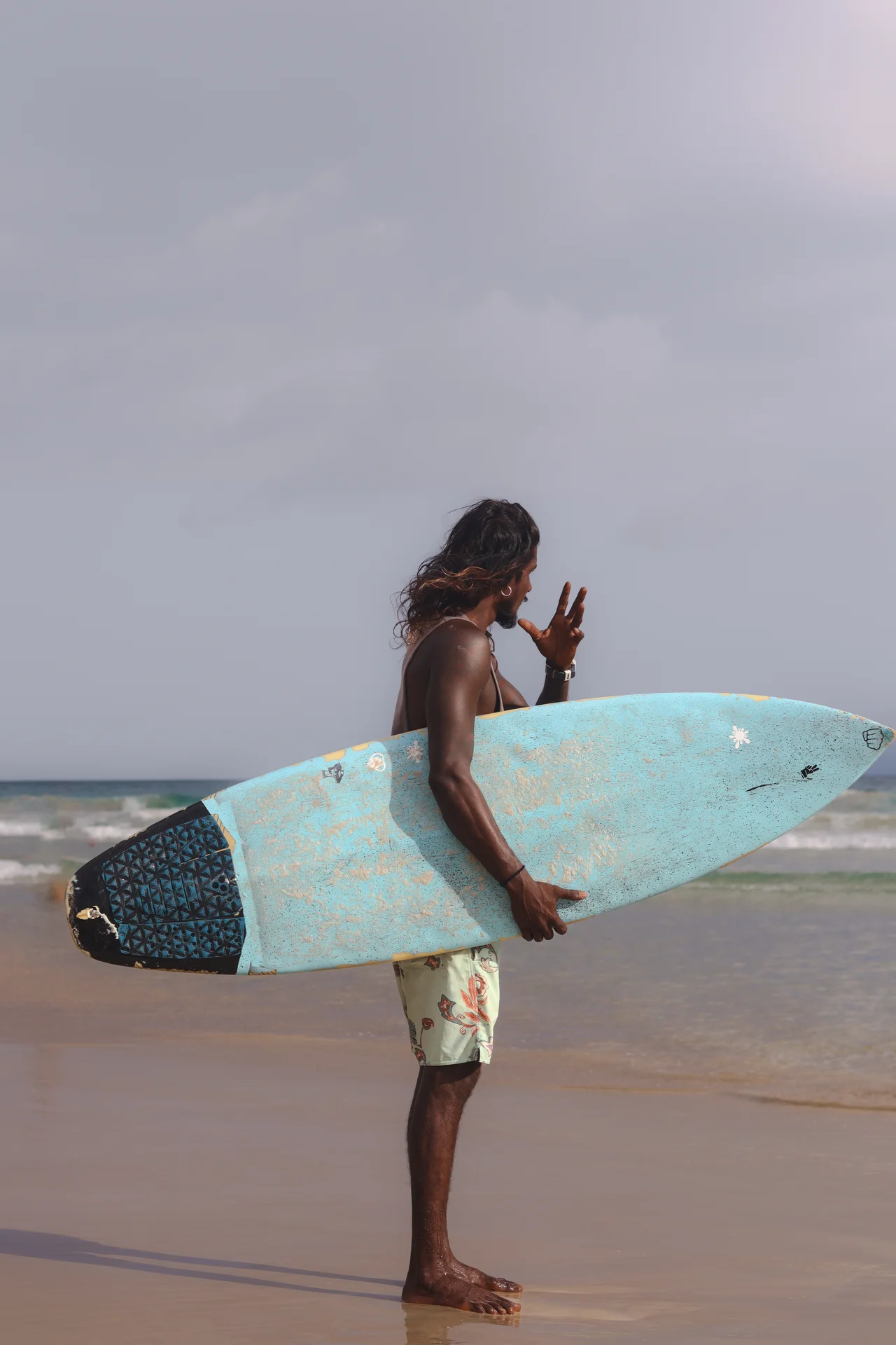 A Home Waves surfer carrying a board along Kabalana Beach